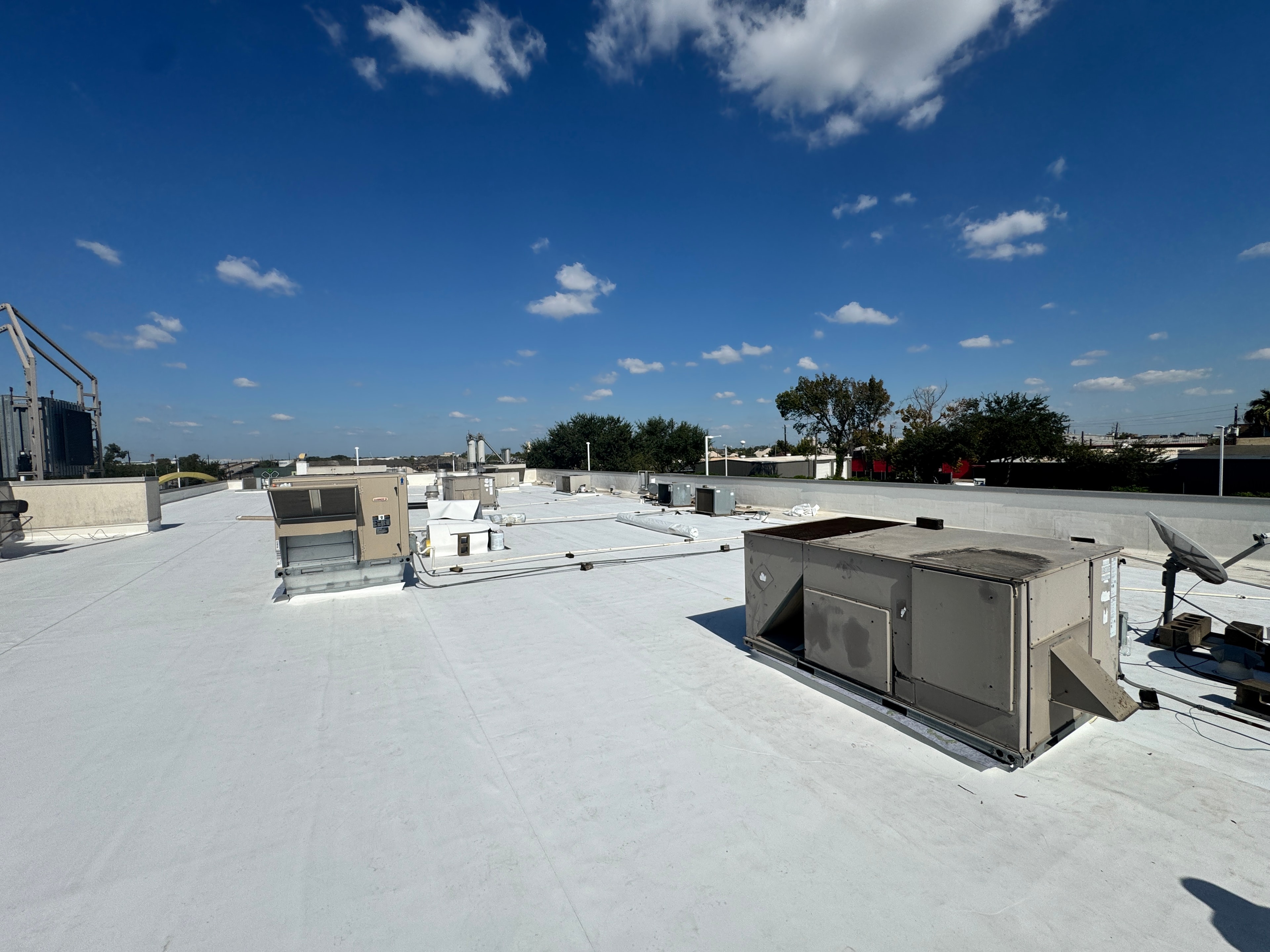 Finished commercial flat roof with HVAC equipment under blue sky