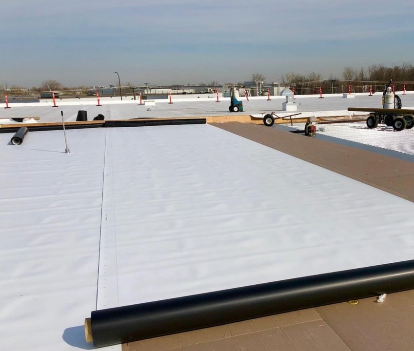 TPO membrane installation in progress with roofing equipment on commercial roof