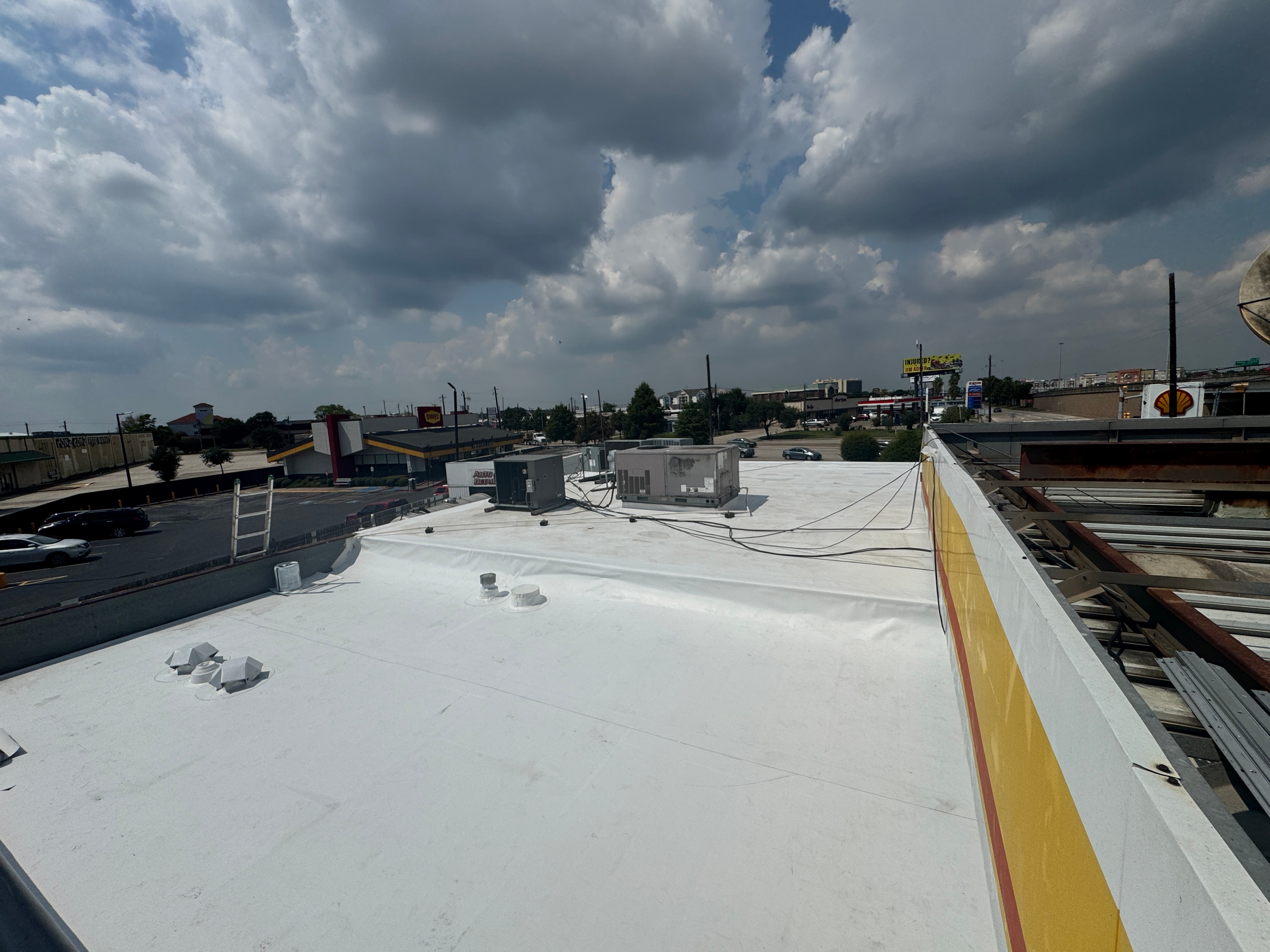 Crew pressure washing commercial metal roof prior to coating