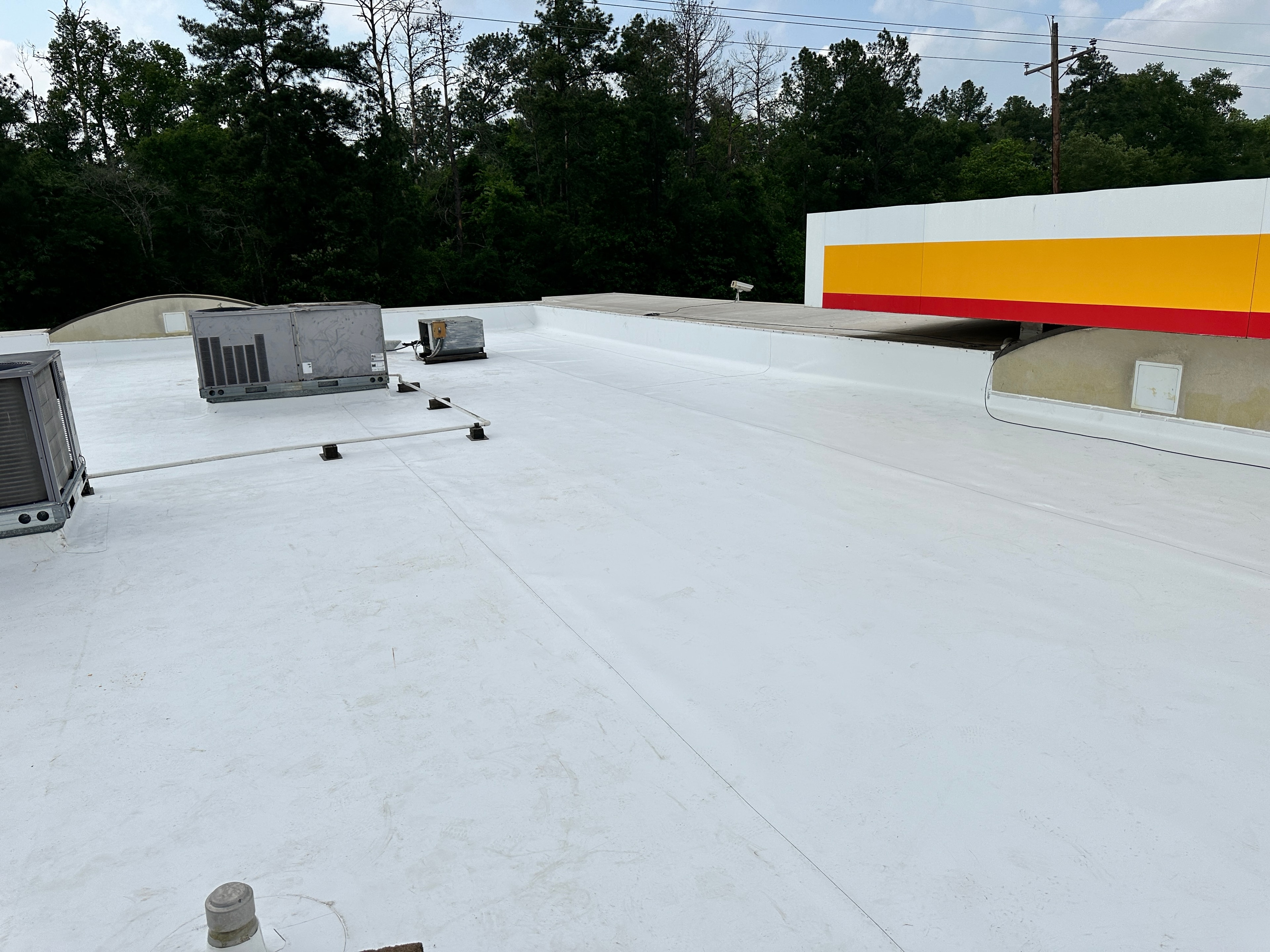 Completed white TPO roof on Shell station with yellow and red brand colors